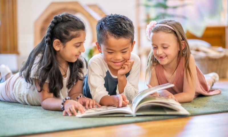 Three children reading a book together, working on empathy
