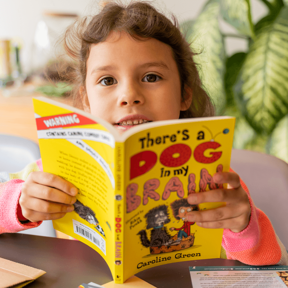 A girl's face peeping out from behind an open, bright yellow chapter books