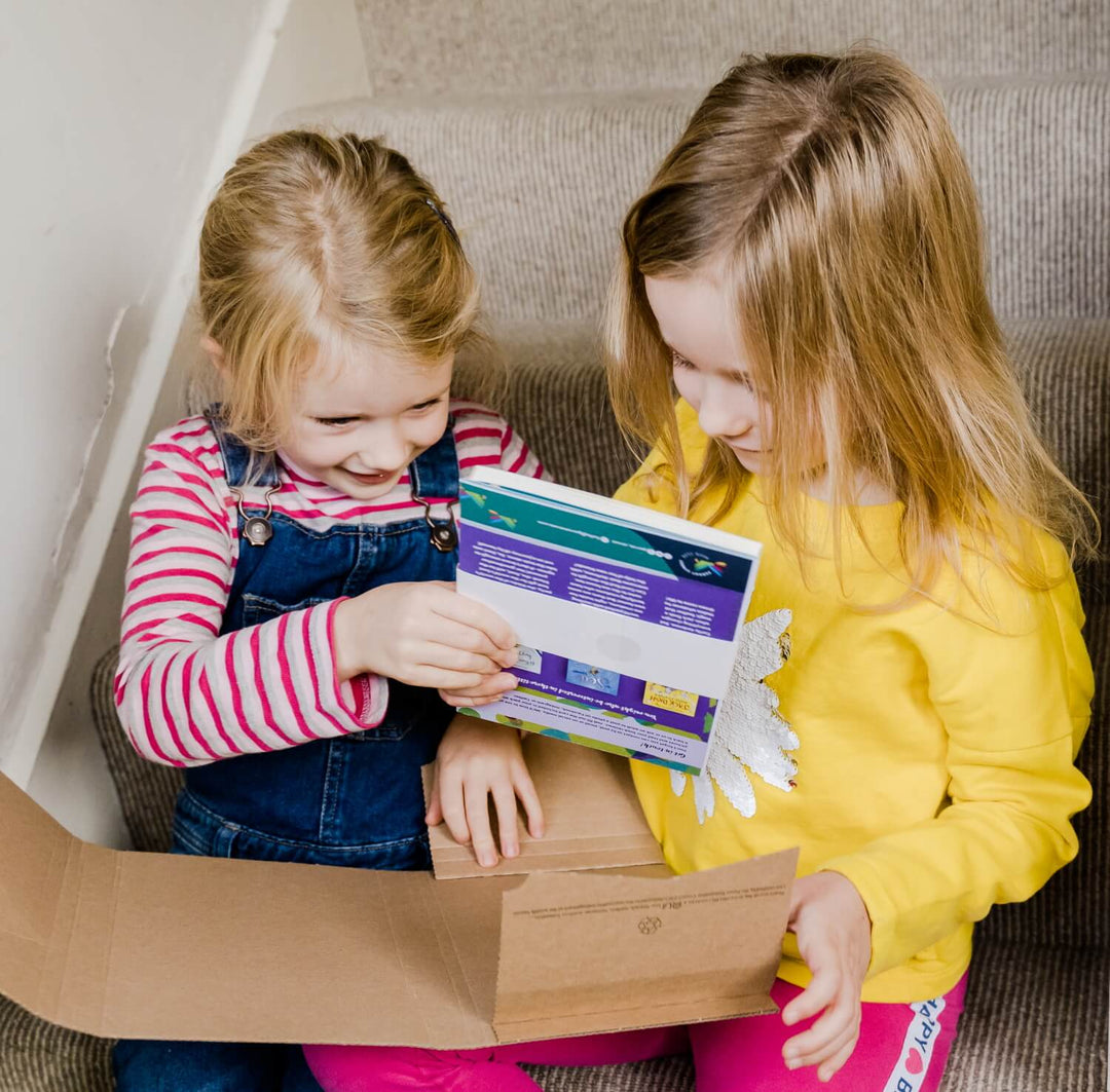 Two girls excitedly unwrapping a Parrot Street Book Club subscription box