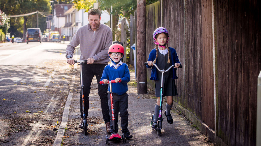 Family scooting along a pavement to school