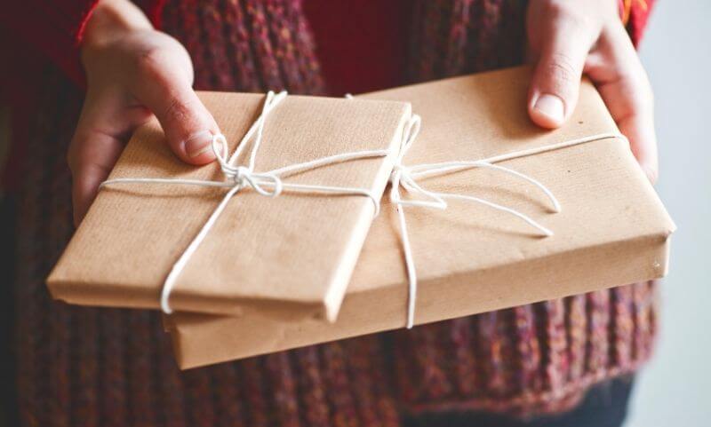 Hands holding two wrapped gifts that look like chapter books