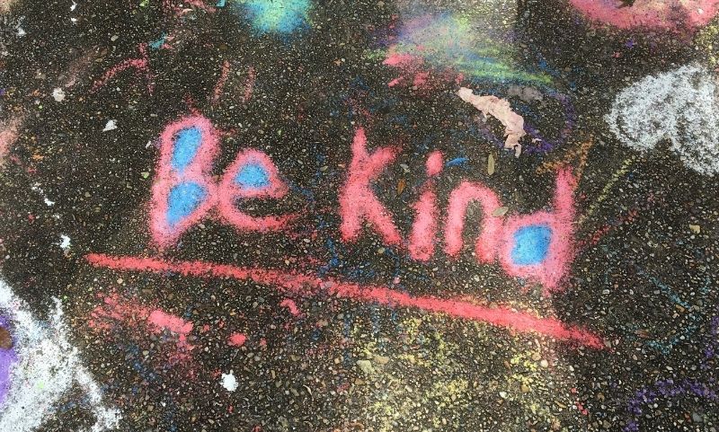 The words be kind written in colourful chalk by a child