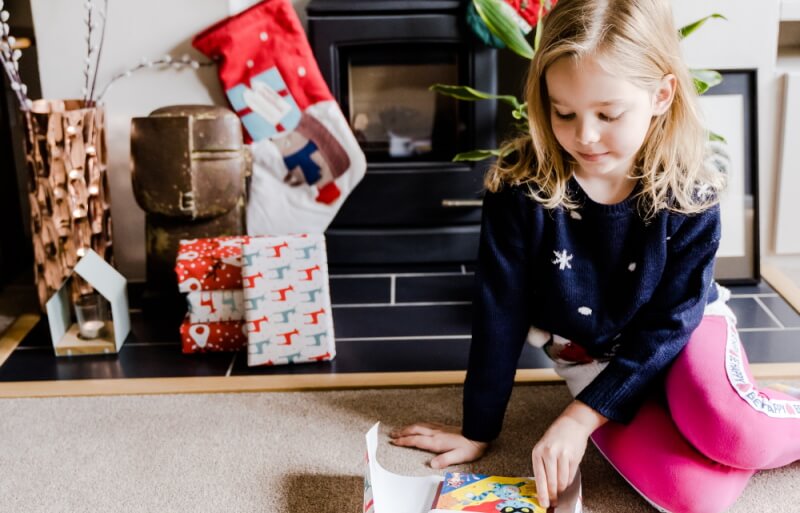 Child unwrapping Parrot Street book at Christmas