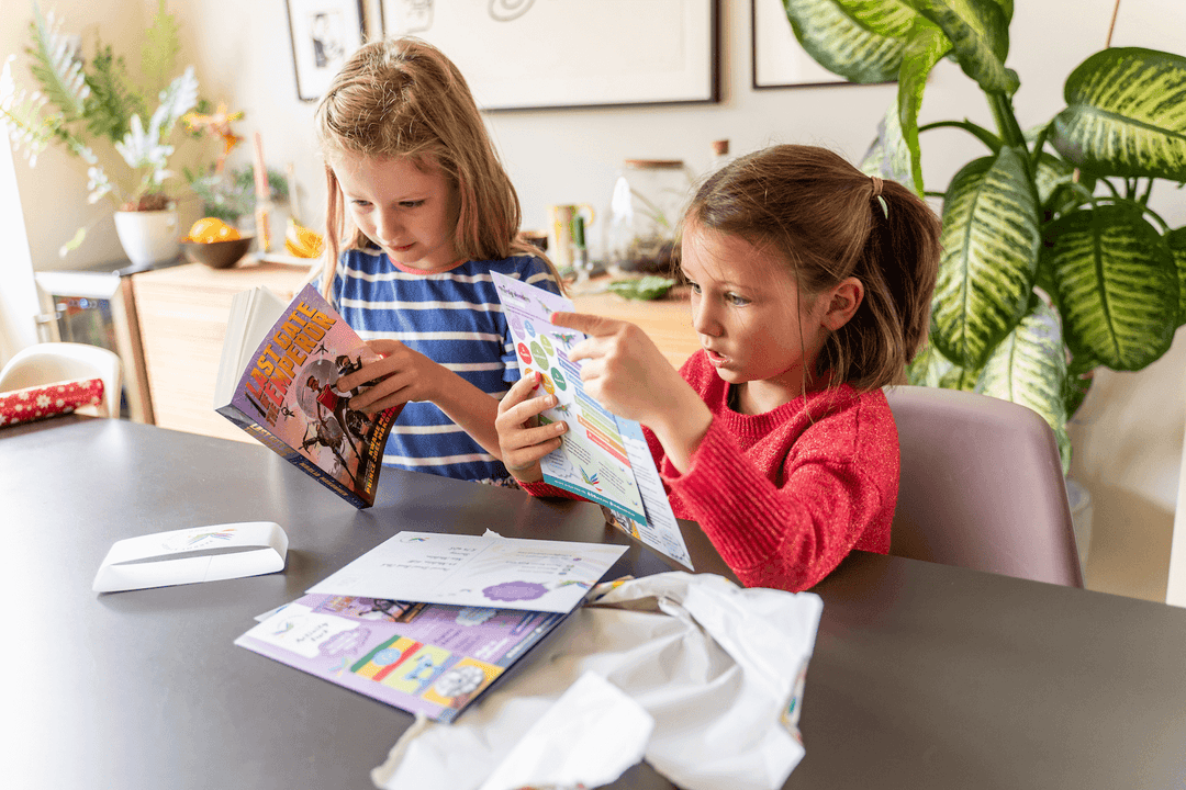 Two children looking at a Parrot Street Book Club book and activity pack from subscription box