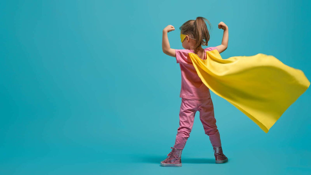 Girl in a yellow cape striking a superhero pose