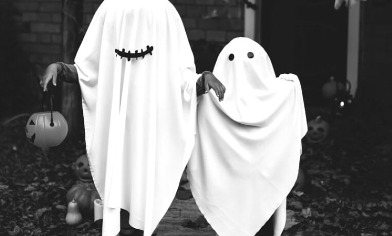 Two children in white sheets, dressed as ghosts.
