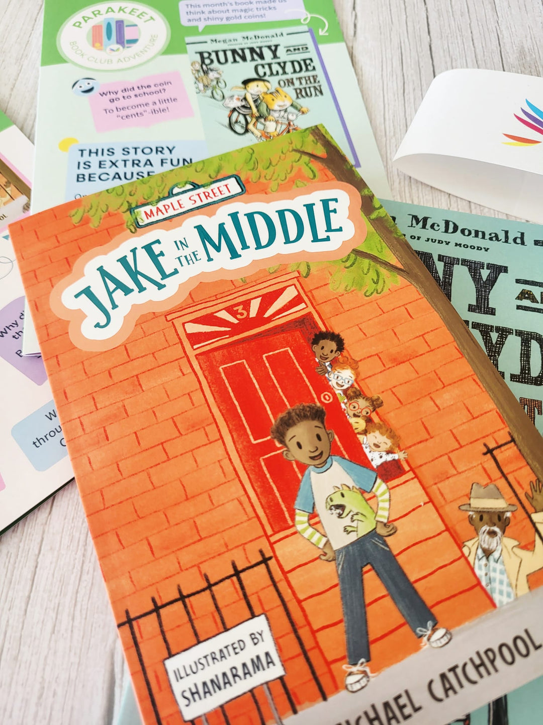 Children's book titled 'Jake in the Middle' by Michael Catchpool on a wooden surface with other books.