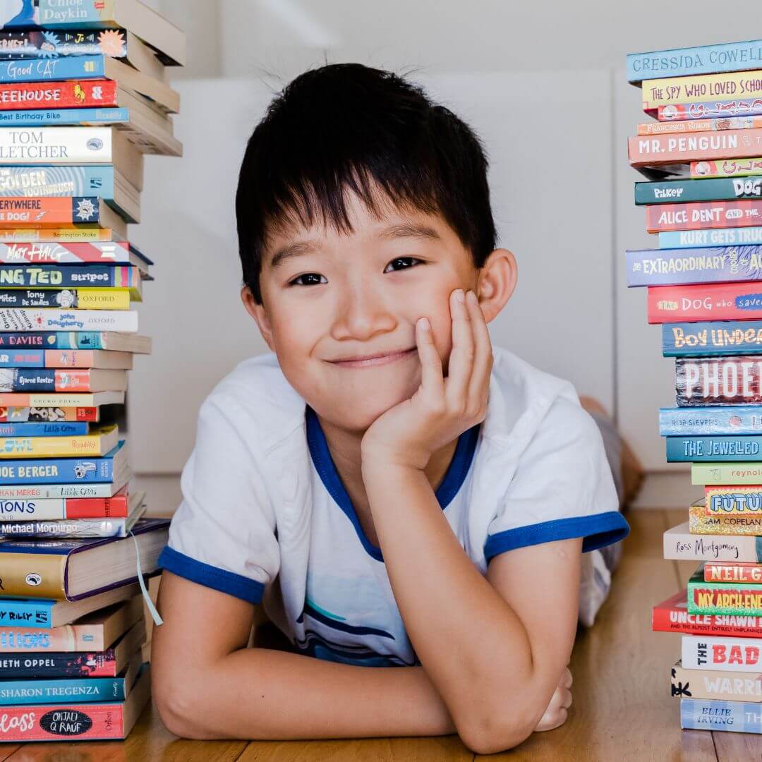 Smiling boy between two large stacks of chapter books