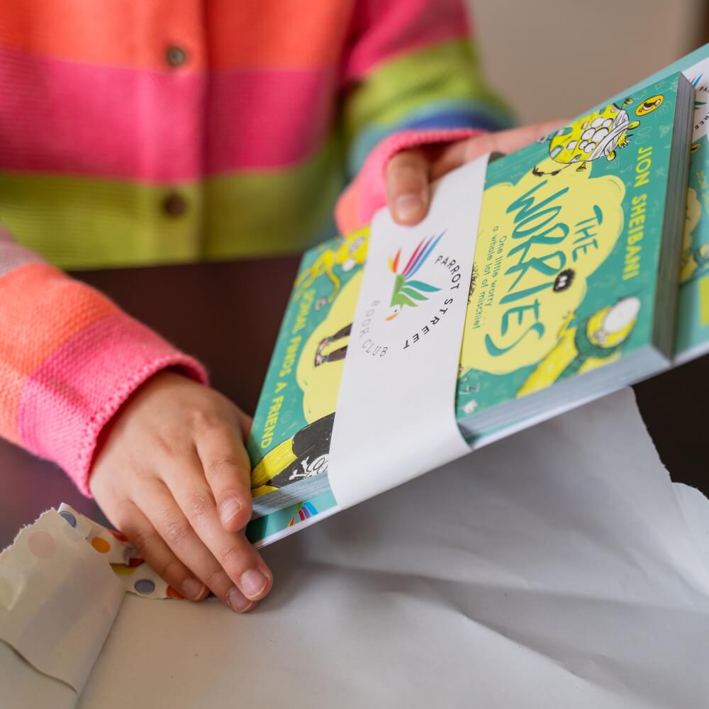 A child's hand holding a book and activity pack bundle of The Worries, a great book for developing empathy