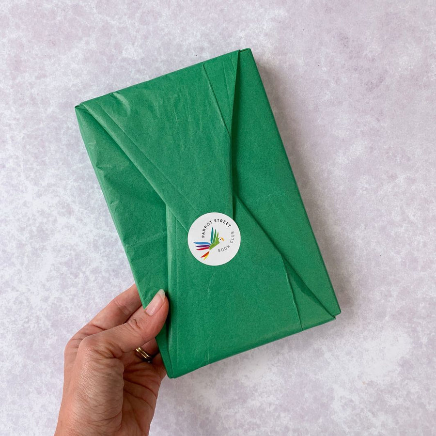 A book wrapped in green tissue paper and sealed with a Parrot Street Book Club sticker