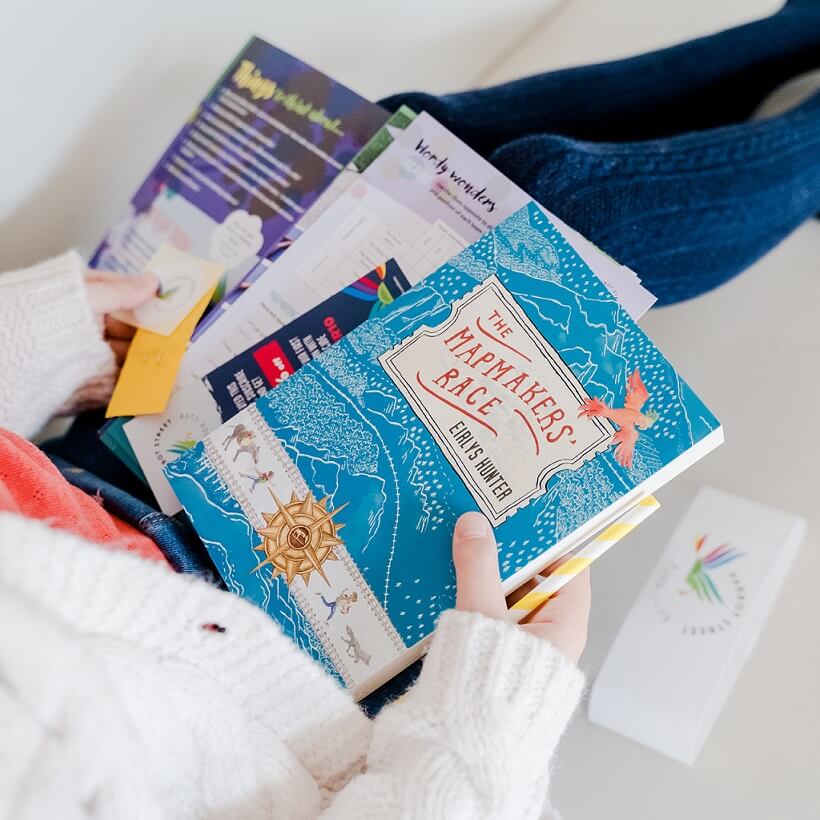 Girl holding an unwrapped Parrot Street Book club subscription box on her lap