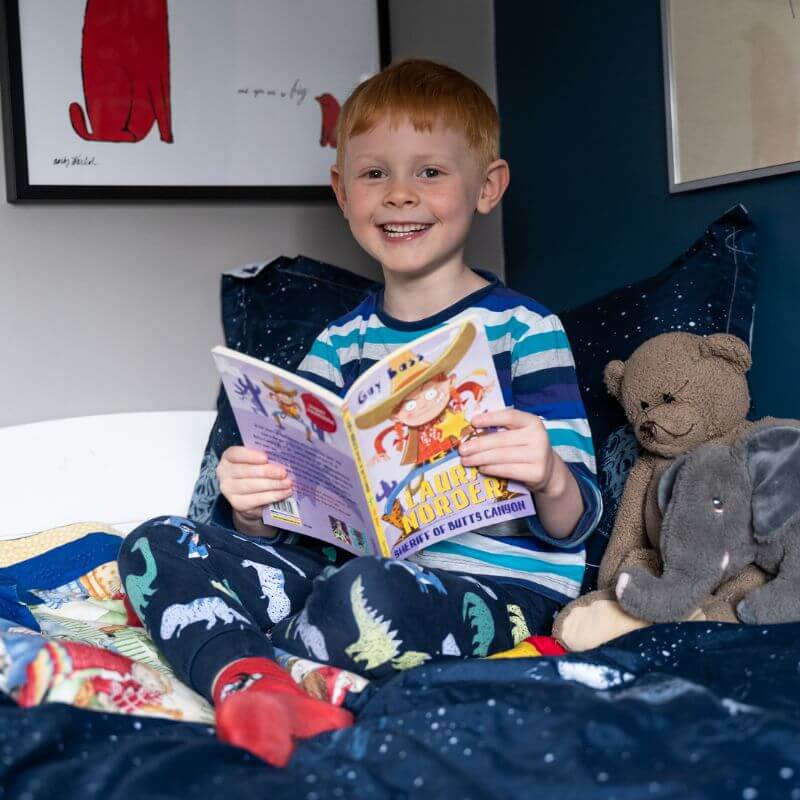 Smiling child holding a chapter book, received in Parrot Street Book Club's children's book subscription box