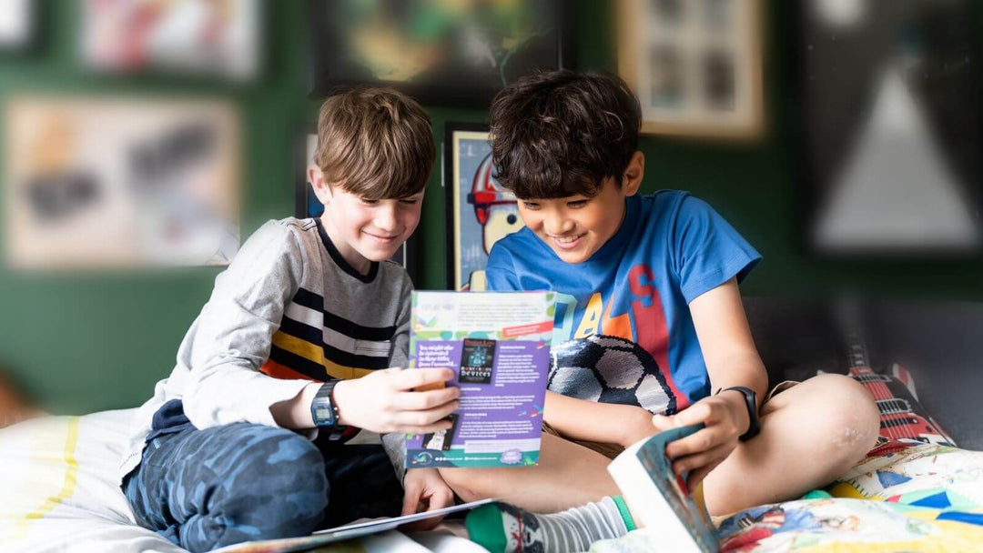 Two children sit cross-legged looking at a Parrot Street Book Club book and activity pack 