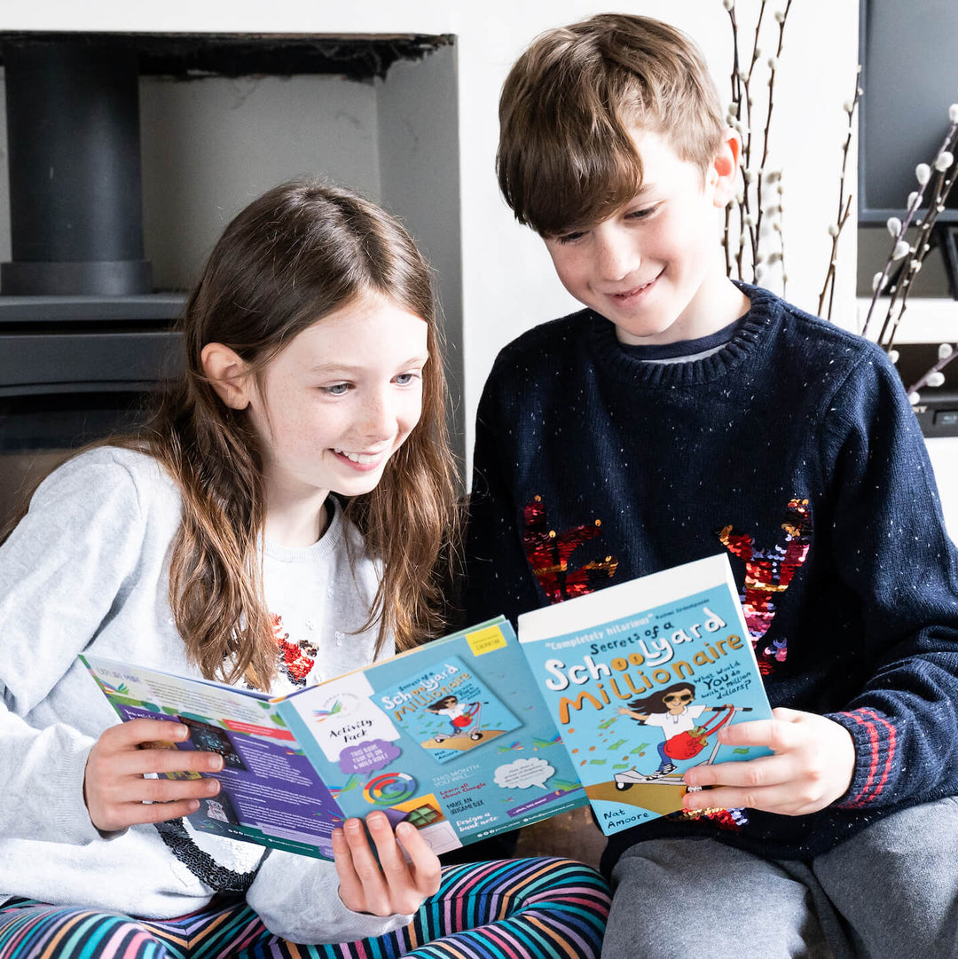 A girl and a boy both looking at a Parrot Street Book Club subscription box book and activity pack