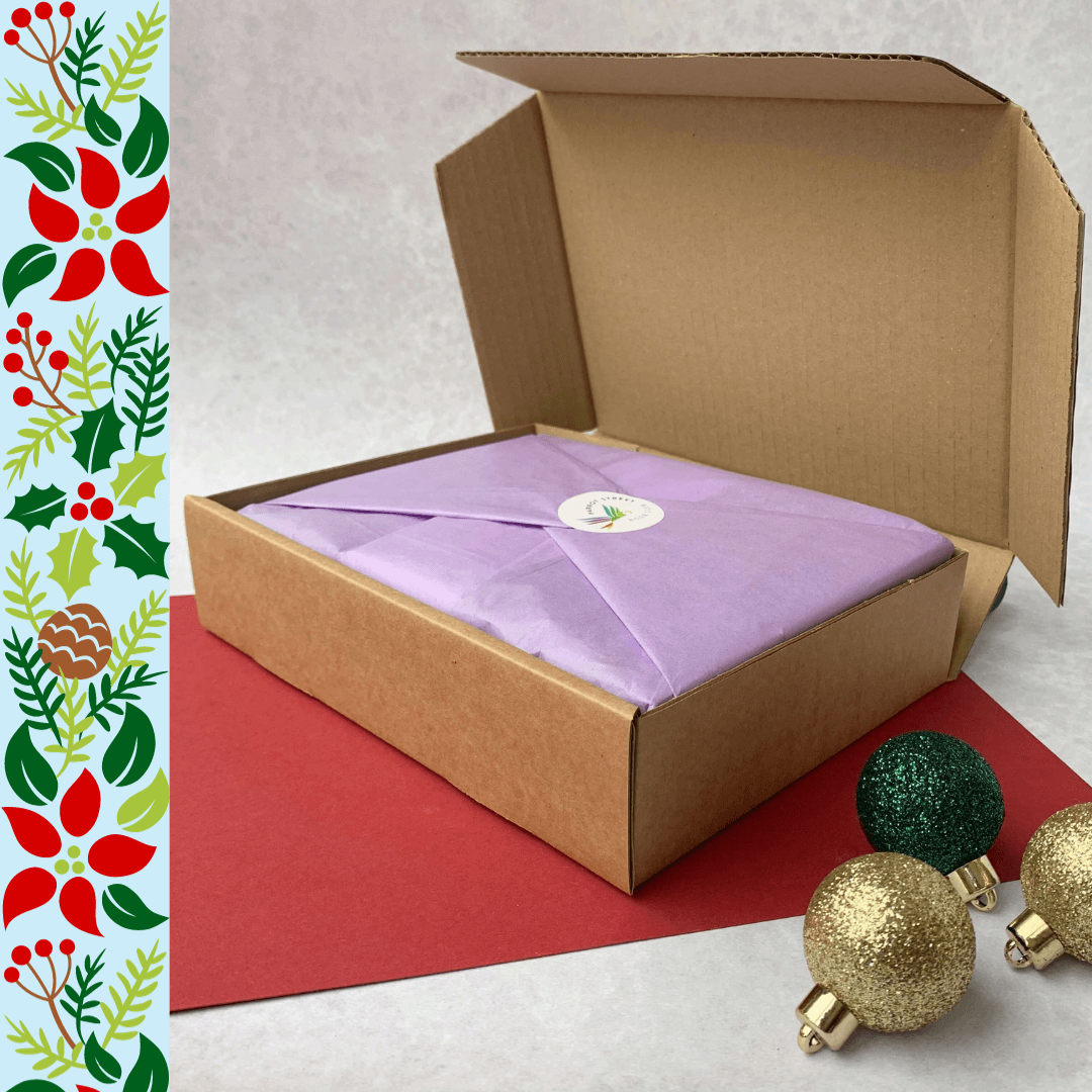 Tissue-wrapped children's book gift set neatly inside a mailing box surrounded by Christmas decorations