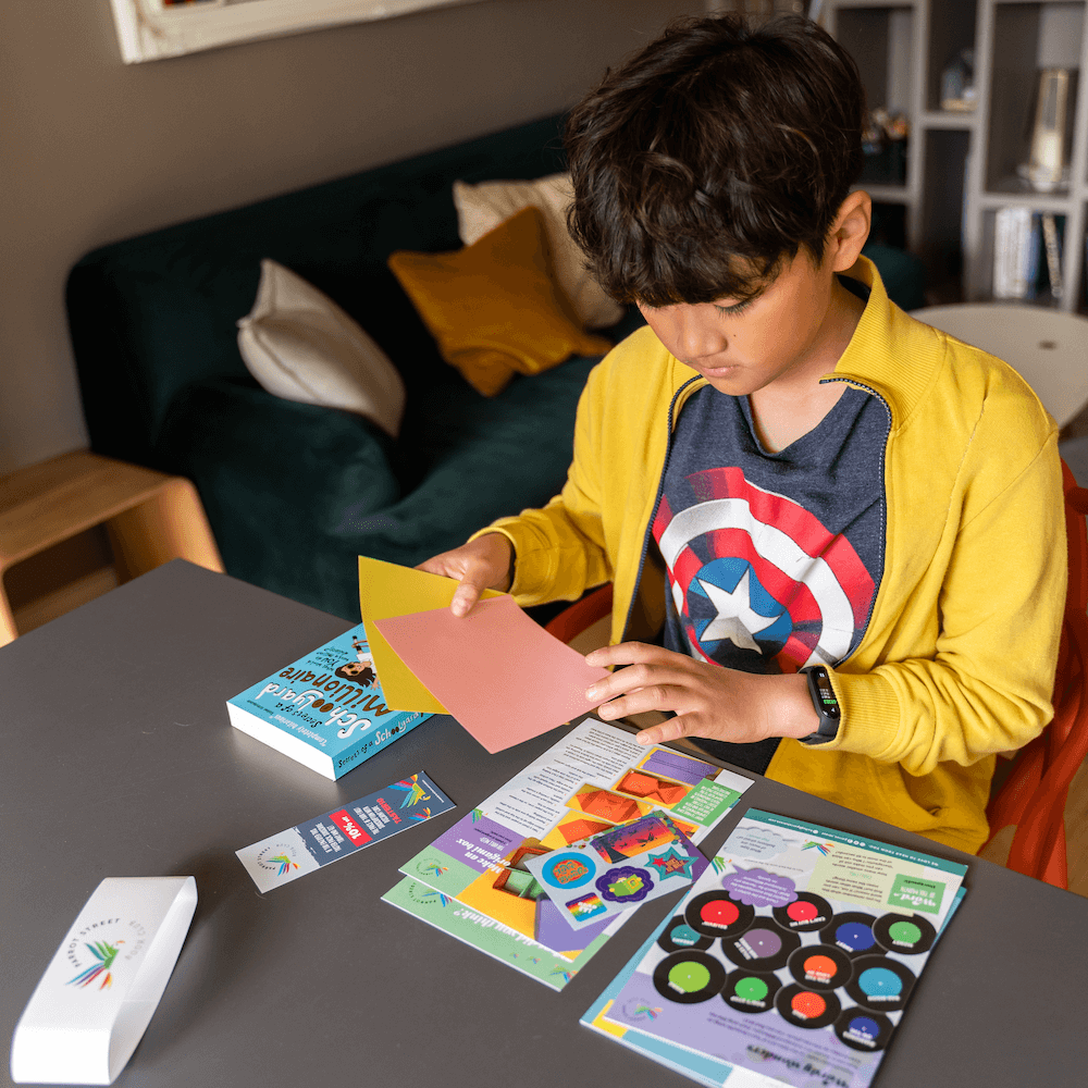 Boy sat at a table exploring a book and activity pack from a monthly subscription box