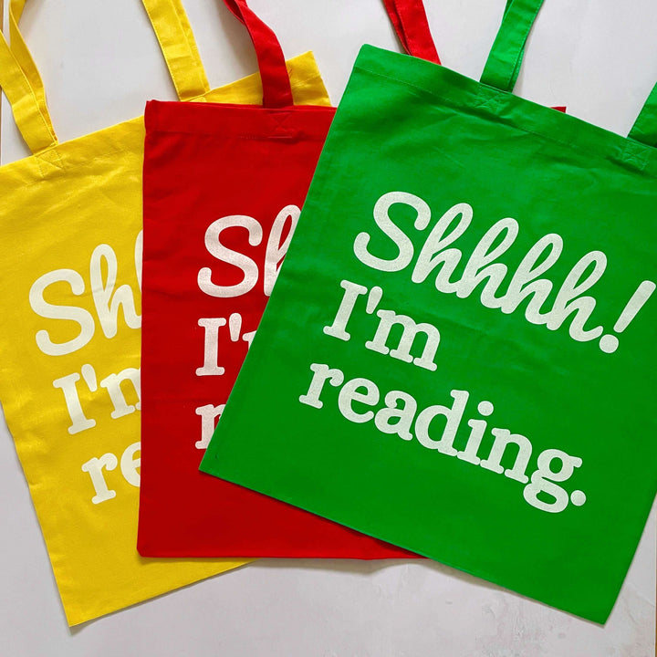 A yellow, red and green version of cotton tote bag for book lovers with the slogan Shhhh! I'm reading. 